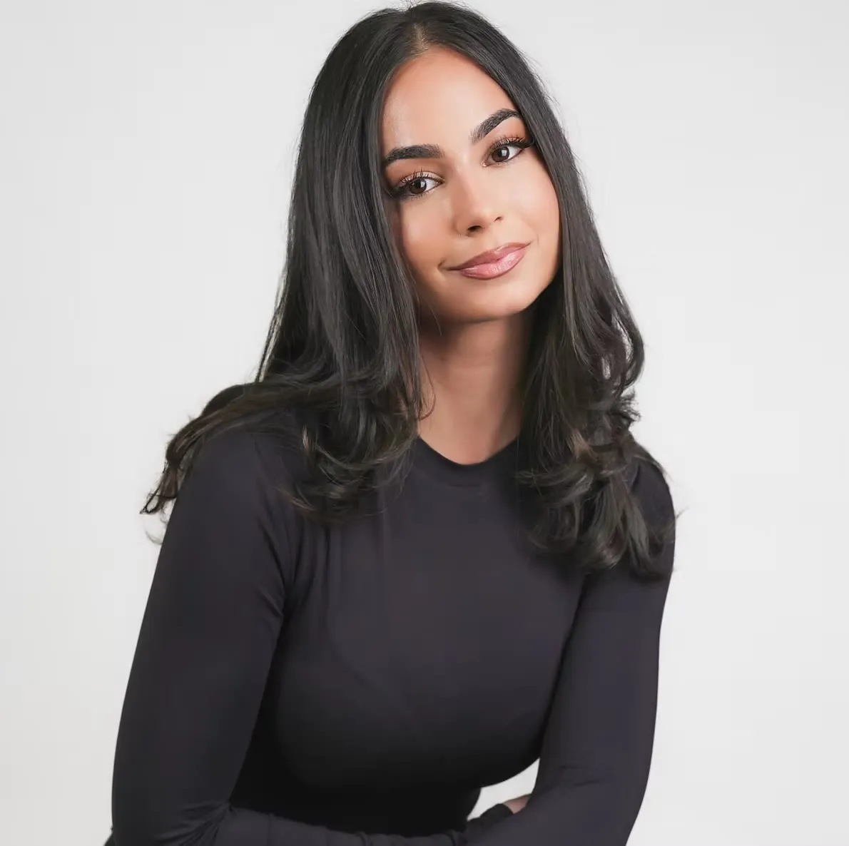 Portrait of Maya El Bayeh in a black top against a pale background.